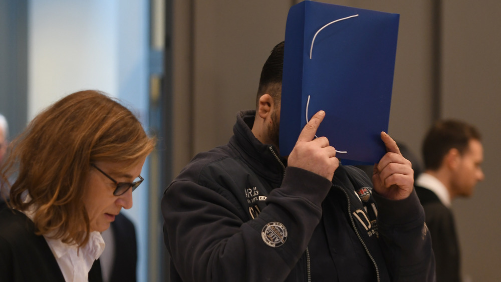 Niels Högel tries to hide from the cameras in court