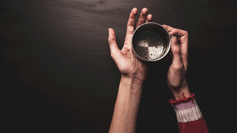 Person holding empty metal cup