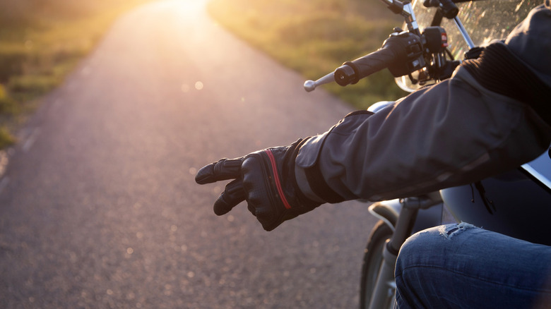 Motorcyclist giving downward peace sign