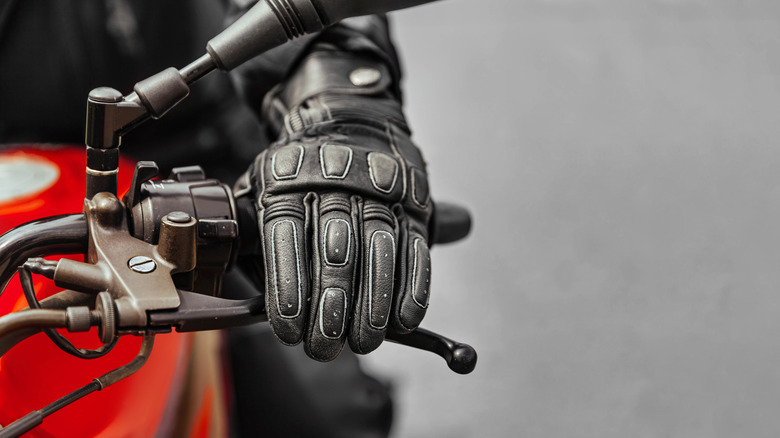 Gloved hand gripping motorcycle handle