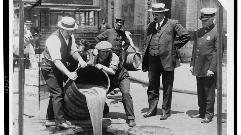 New York City Deputy Police Commissioner John A. Leach, right, watching agents pour liquor into sewer following a raid during the height of prohibition 