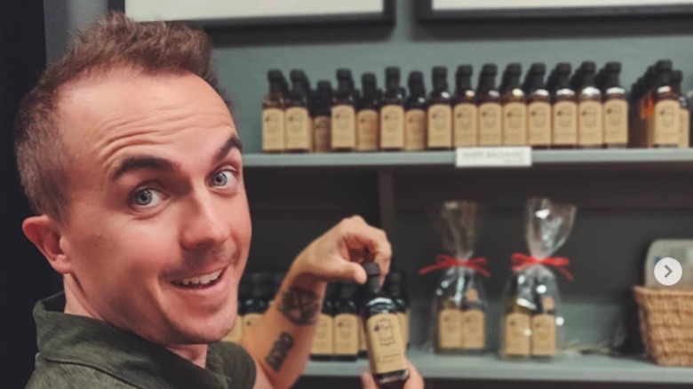 Frankie Muniz posing with bottles of olive oil in his store