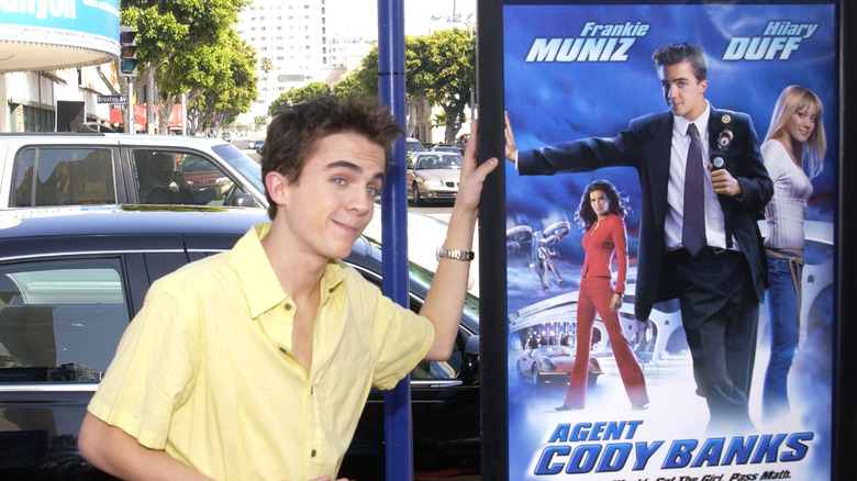 Frankie Muniz posing with movie poster for Agent Cody Banks