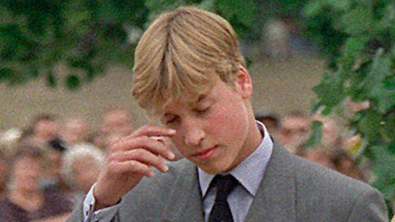 Prince William looking at the flowers left for his mother