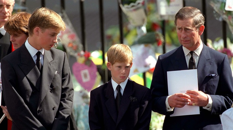 Princes Harry, William, and Charles looking at the flowers left for Princess Diana