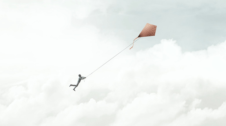 man with large kite floating away