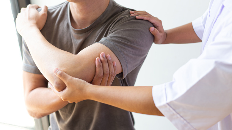 therapist helps man with muscle pain