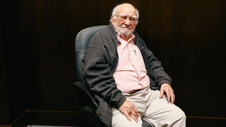 Ed Asner sitting in chair