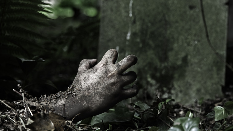 A hand busting through the grave in a cemetery