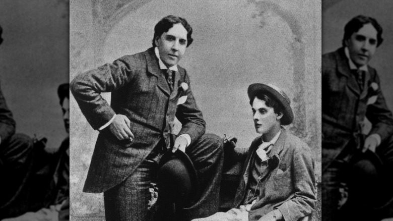 Oscar Wilde standing with Alfred Douglas sitting