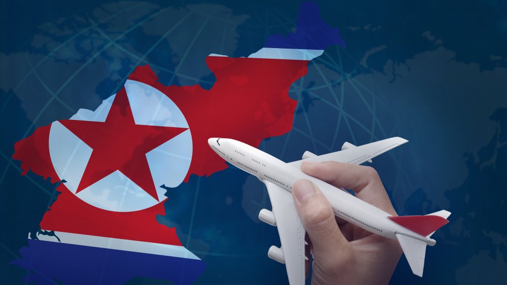 A hand holding an airplane over a map of North Korea