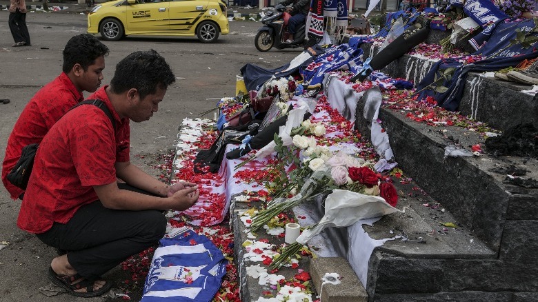 People kneeling at roadside memorial