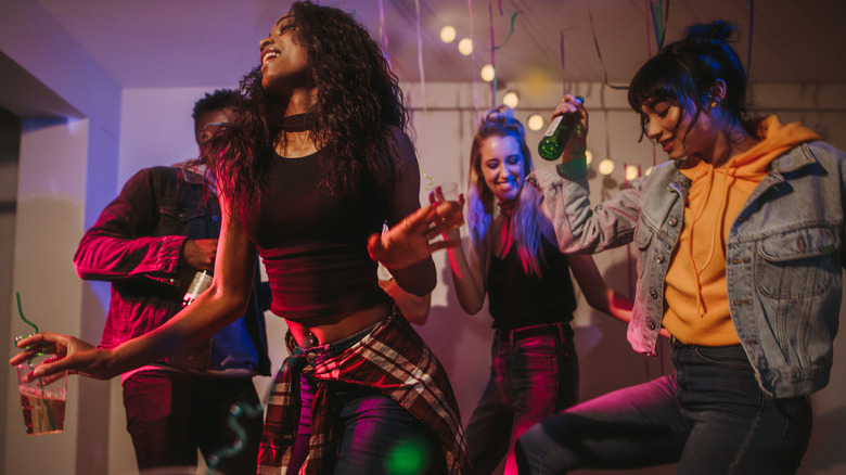 dancing holding drinks at house party. 