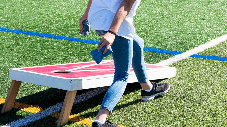 Cornhole player holding bags in front of platform