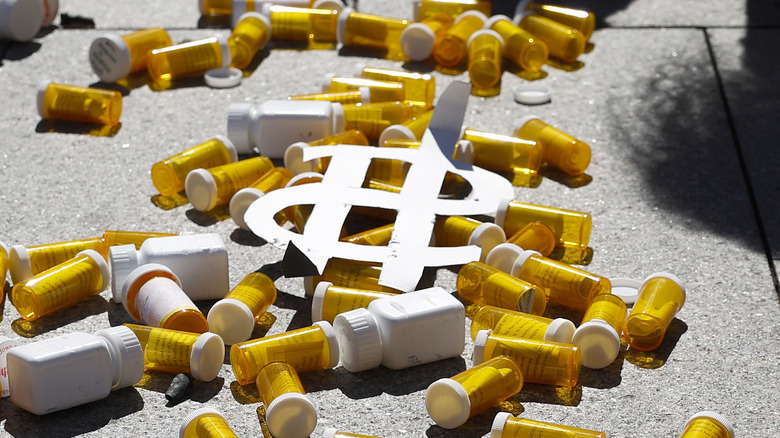 Scattered pill bottles sidewalk surrounding dollar sign