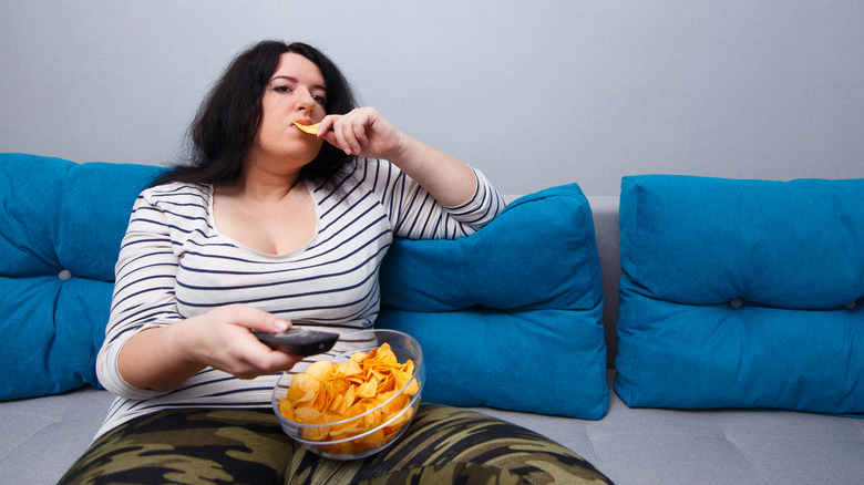 Woman sitting with romote and chips