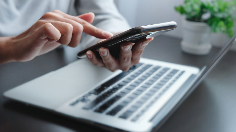 Person using smartphone and laptop