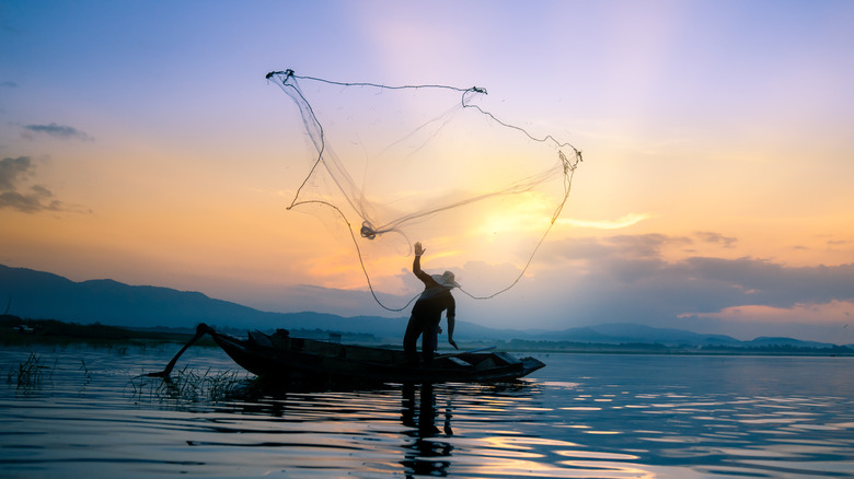 fisherman throws net into the sea