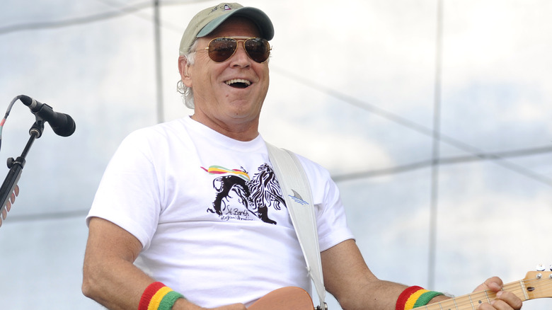 Jimmy Buffett playing guitar smiling