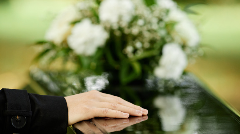 person's hand on casket 