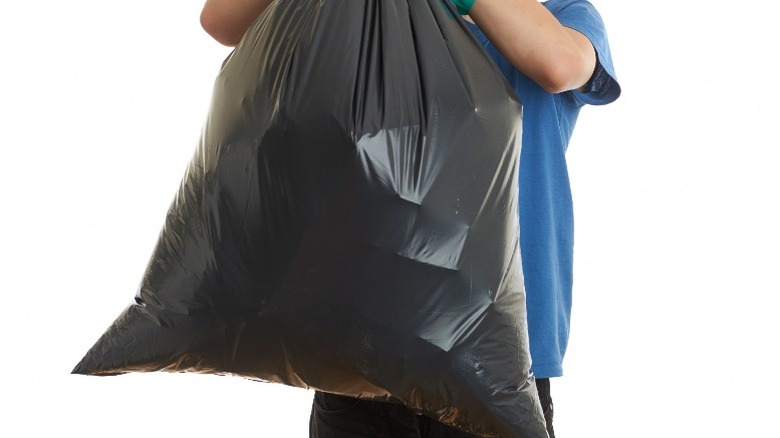 man hoisting trash bag