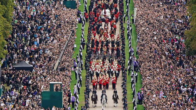 Crowds watch a funeral procession