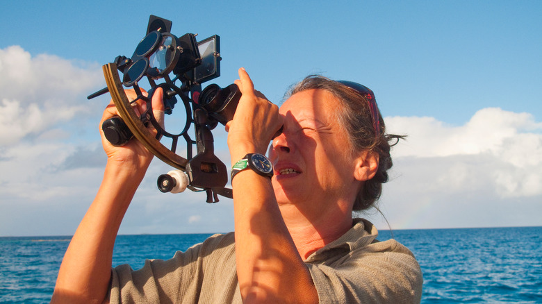 woman using a sextant at sea