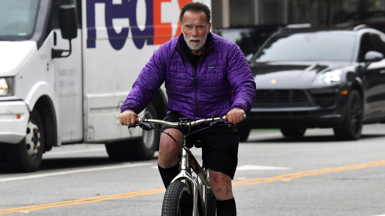 Arnold Schwarzenegger bikes in front of a FedEx truck