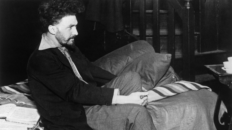 Ezra Pound sitting on a bed