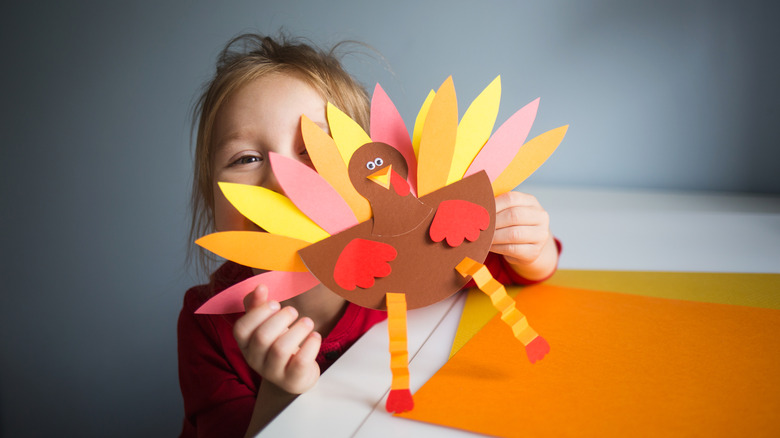 child holding a paper turkey