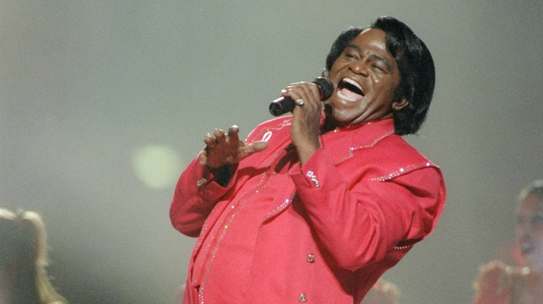 James Brown on stage in pink suit with microphone