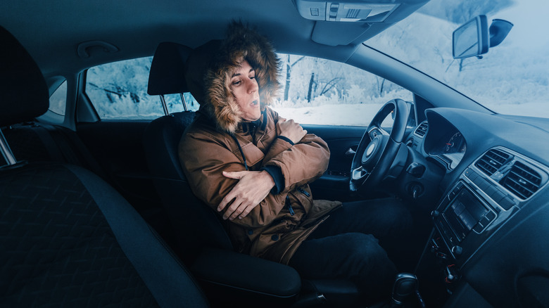 Man in parka coat keeping warm in car in storm