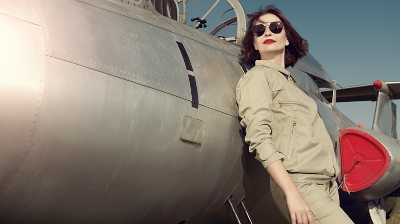 Female pilot posing by airplane