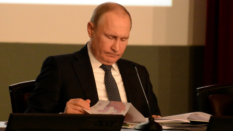 Vladimir Putin looking down at book