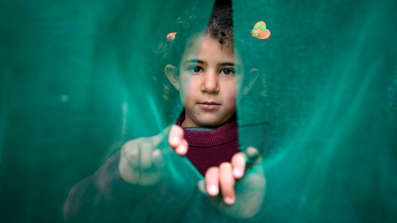 child looking through torn fabric