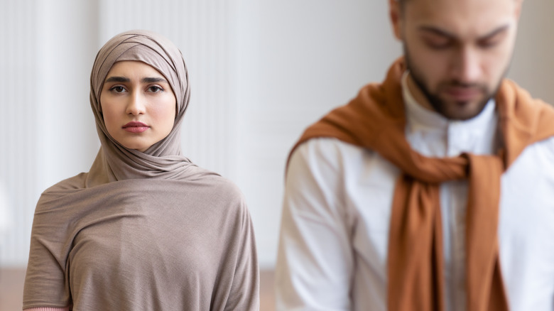 muslim woman standing behind husband