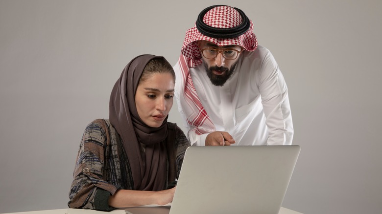 muslim woman and man looking at computer