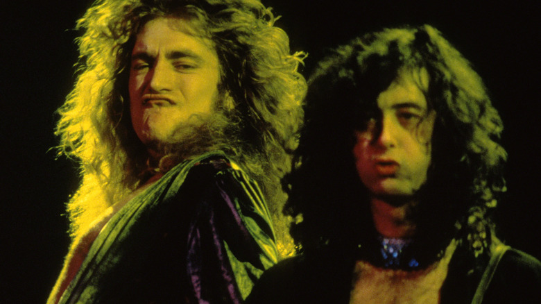 robert plant making a face while jimmy page plays guitar during a led zeppelin concert