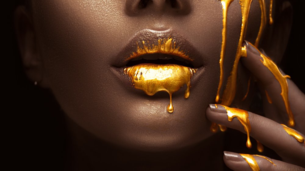 Gold paint dripping on a Black woman's face