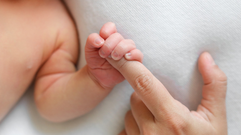 Baby holding parent's finger