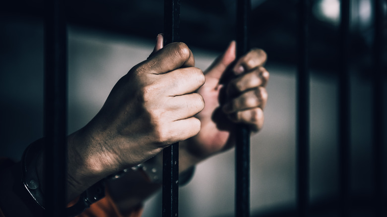 woman's hands on prison bars