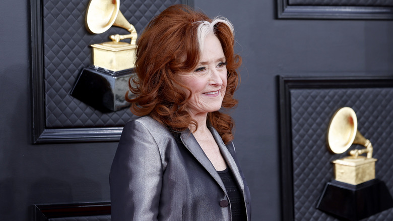 Bonnie Raitt poses beside awards