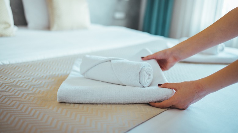 Maid placing towels on bed