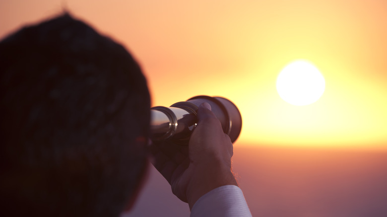 Dude looking through telescope at horizon