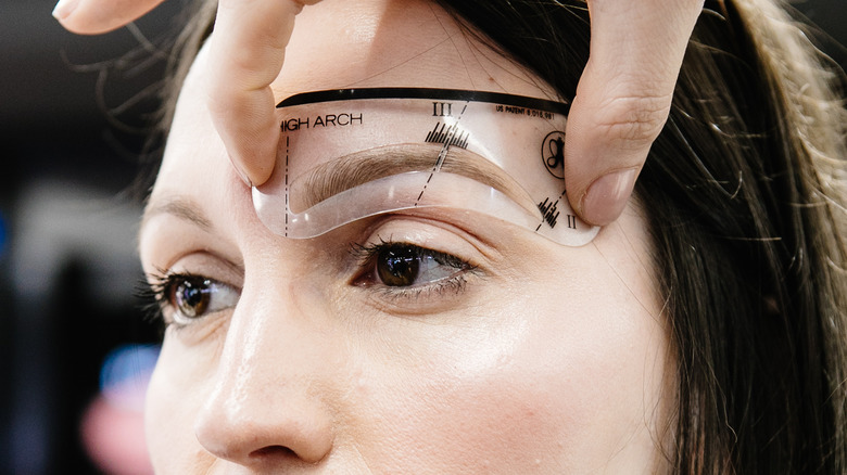 Woman having eyebrow shape measured