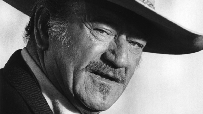 John Wayne looks from underneath hat