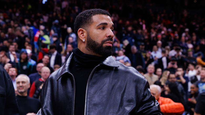 Drake in dark jacket at basketball game