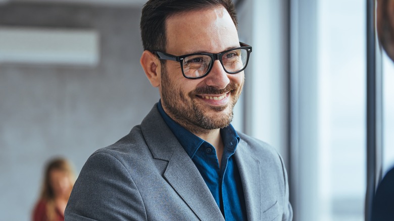 bespectacled man smiling in office