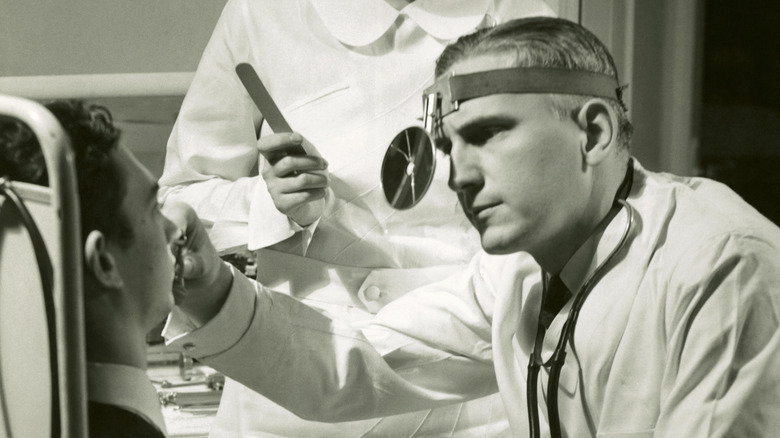 a doctor examining a patient 1950s