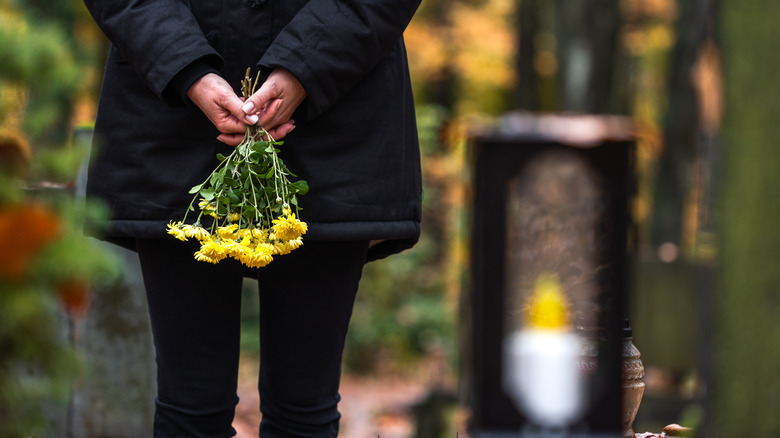 a person holding flowers at a graveyard